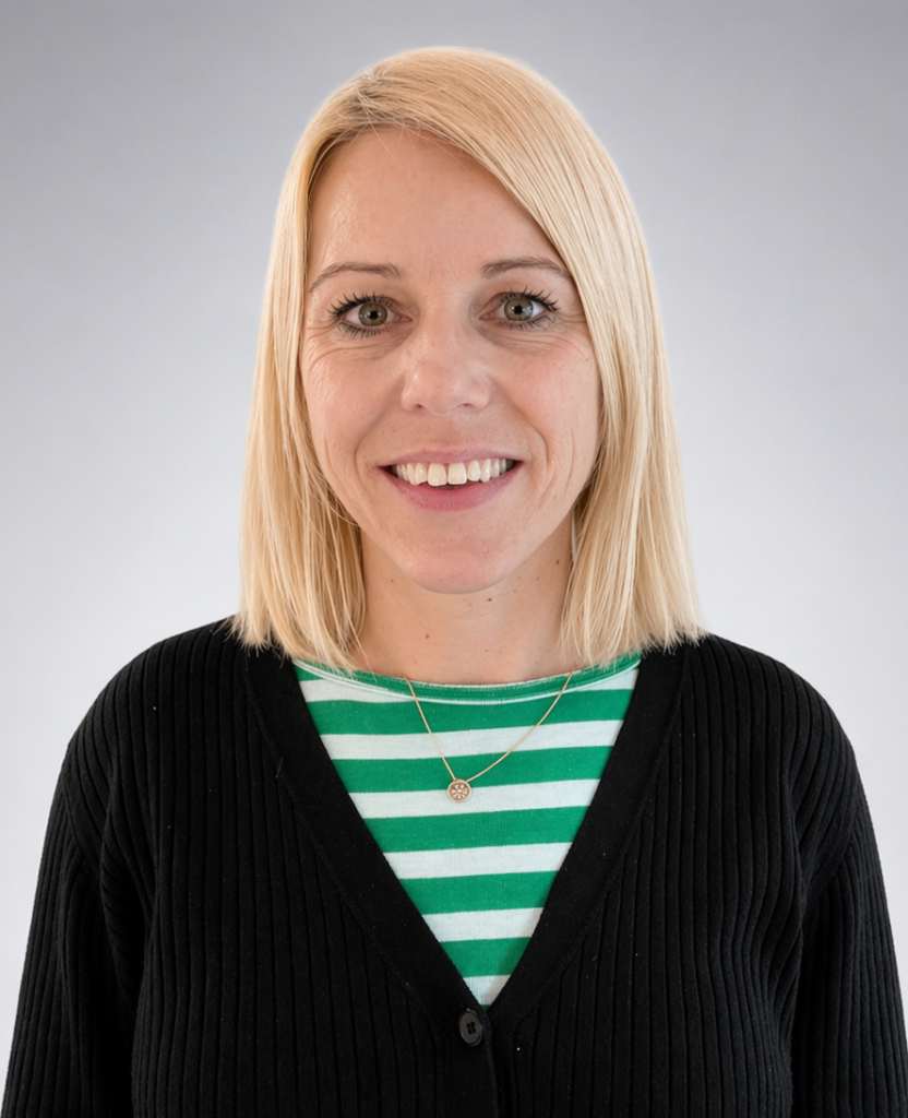 Eine Frau mit blondem Haar und einem Lächeln, trägt ein gestreiftes grünes Shirt und eine Halskette.